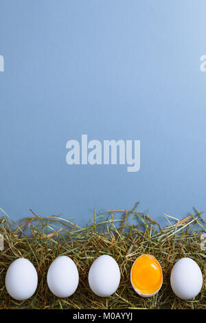 White eggs is laying in row, one of them is bisected and shows yolk. Stock Photo
