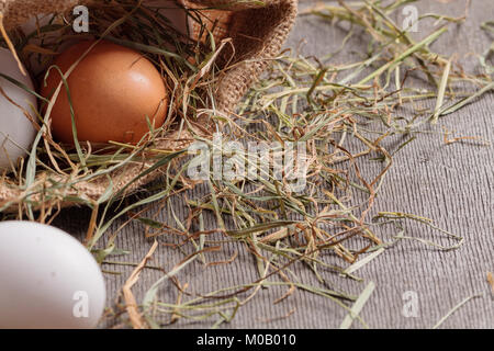 Rural eggs in jute bag with scattered hay around. Stock Photo