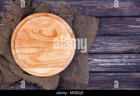 Round cutting board on old wooden texture background. Top view Stock Photo