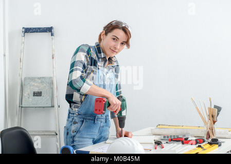 a pretty young smiling woman using cordless drill Stock Photo