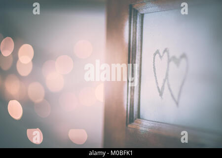 Open doors to love, two handwriting hearts on the open door, festive blurry bokeh lights behind, conceptual photo of first affection or true love Stock Photo