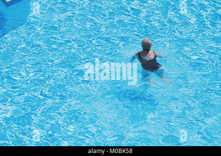 Old Woman in Blue Swimming Pool on a Summer Day Stock Photo