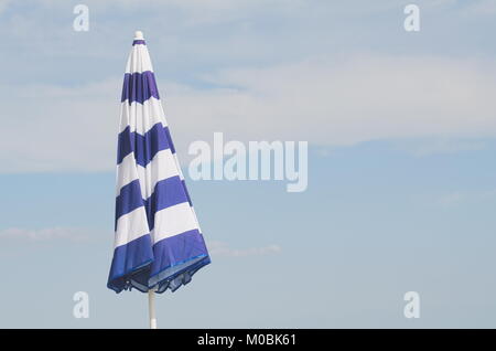 Blue and White Striped Closed Parasol against Summer Blue Sky Stock Photo