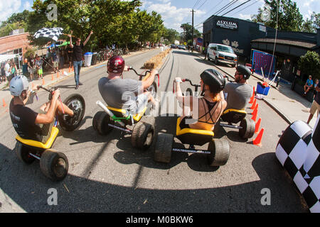 Atlanta, GA, USA - September 23, 2017:  People race each other on adult big wheels in a friendly competition at the East Atlanta Strut, a fall festiva Stock Photo