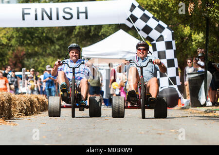 Atlanta, GA, USA - September 23, 2017: Two men race each other on adult big wheels in a friendly competition at the East Atlanta Strut festival. Stock Photo
