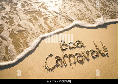 Boa Carnaval message in Portuguese (Happy Carnival in English) handwritten on smooth sand beach Stock Photo