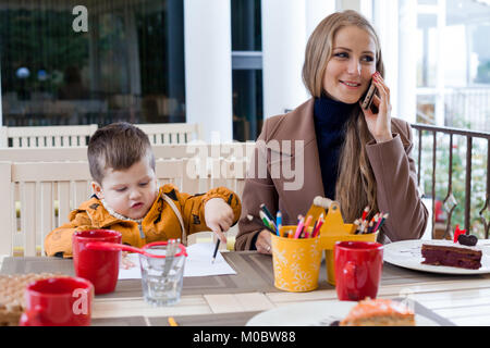 Restaurant mom with son talking on the phone Stock Photo