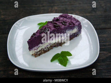 Piece of blueberry vegan pie laying on the white plate garnished with a sprig of mint Stock Photo