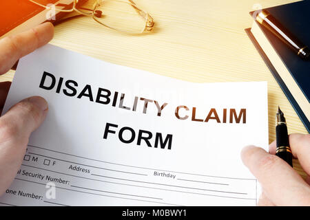 Man holding disability claim form for insurance. Stock Photo
