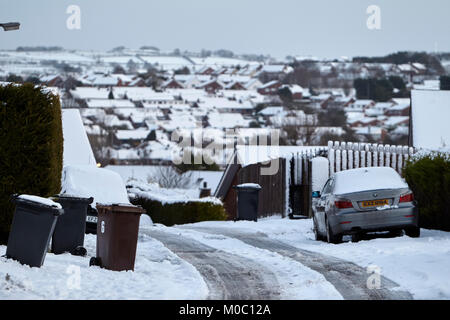 bins left out and cars parked on footpaths with clear centre of suburban street covered in snow in newtownabbey northern ireland Stock Photo