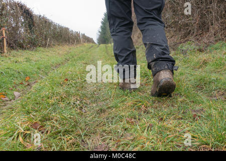 Legs of a woman walking in the  countryside clearly showing muddy hiking boots and dirty trousers Stock Photo