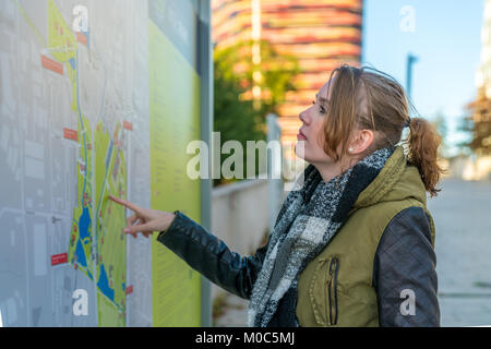 Smiling woman is studying the route map in Hamburg Stock Photo