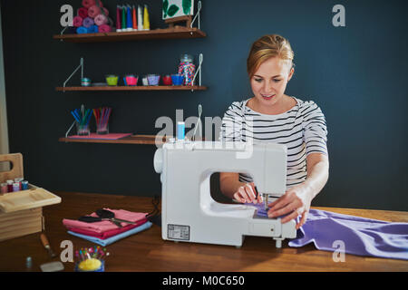 Female designer working at creative office using sewing machine Stock Photo