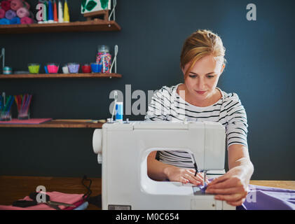 Female designer working on sewing machine on a piece of clothes Stock Photo