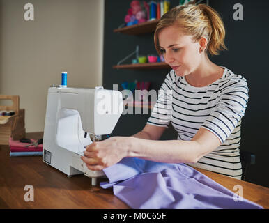 Woman sewing on sewing machine at creative office Stock Photo