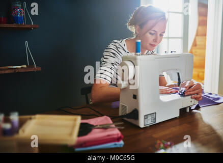 Woman sewing on sewing machine looking satisfied Stock Photo