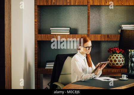 Businesswoman wearing glasses using digital tablet in office Stock Photo