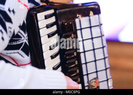 Accordion in the hands of an interpreter, with shallow depth of field and selective focus on keyboards of musical instrument. Stock Photo