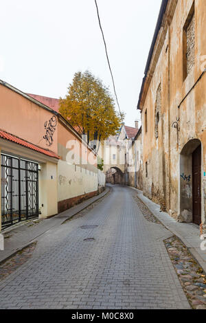 Street view, the narrow Sv Kazimiero Gatve with old dilapidated arch built over the road in the Old Town of Vilnius, capital city of Lithuania Stock Photo