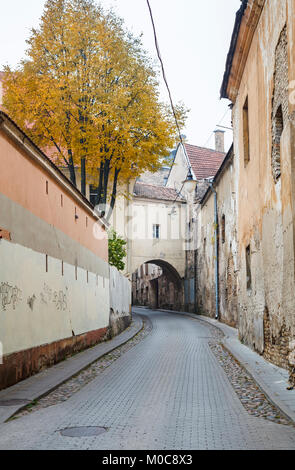 Street view, the narrow Sv Kazimiero Gatve with old dilapidated arch built over the road in the Old Town of Vilnius, capital city of Lithuania Stock Photo