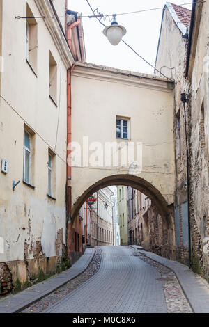 Street view, the narrow Sv Kazimiero Gatve with old dilapidated arch built over the road in the Old Town of Vilnius, capital city of Lithuania Stock Photo