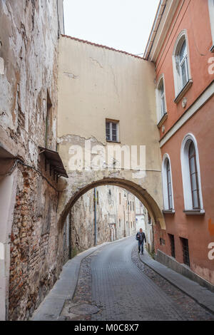 Street view, the narrow Sv Kazimiero Gatve with old dilapidated arch built over the road in the Old Town of Vilnius, capital city of Lithuania Stock Photo