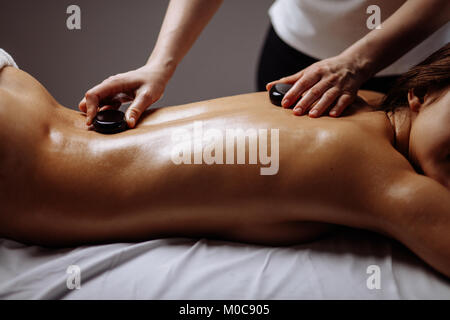 young Woman getting hot stone massage at spa salon Stock Photo