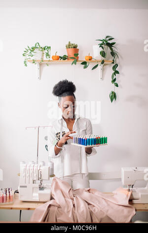 african seamstress holding coils with threads Stock Photo