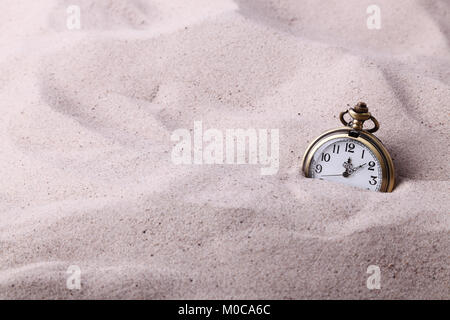 Vintage pocket watch partially buried in the sand Stock Photo