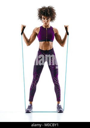 Fitness girl performs exercises with resistance band. Photo of girl with beautiful athletic body isolated on white background. Strength and motivation Stock Photo