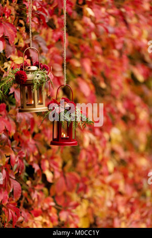 Fall time. Autumn decoration. Candlesticks in the form of lanterns with daisy decor, juniper and autumn red leaves. Selective focus. Stock Photo