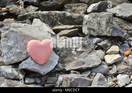 Pink bath salt figure in a heart shape on a rocky beach Stock Photo