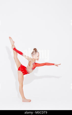 Little girl in red dress doing standing split. Stock Photo