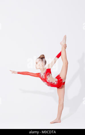 Little girl in red dress doing standing split. Stock Photo