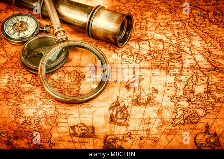 Vintage compass, magnifying glass, pocket watch, quill pen on an old ancient map in 1565. Vintage still life. Stock Photo