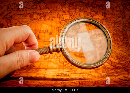 Vintage still life. Vintage magnifying glass lies on an ancient world map in 1565. Stock Photo