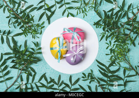 Easter colored eggs decorated with ribbon on floral background.