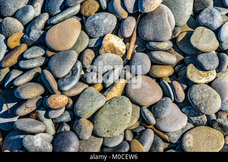Rounded stones in blue and orange colors near beach Stock Photo