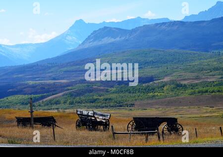 On a hilltop, sits three old historic wooden wagons, from the cowboy days, with an amazing mountain and valley landscape view Stock Photo