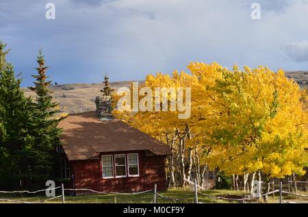 An old historic mountain cabin, sits nestled among the autumn colored trees Stock Photo