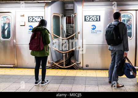 New York City, USA - October 27, 2017: Two young people in underground platform transit by 42 street sign in NYC West Side Subway Station after work o Stock Photo