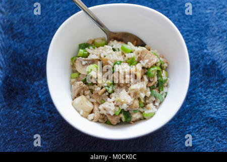 pork meat of mushrooms and rice in a white bowl on a blue background Stock Photo