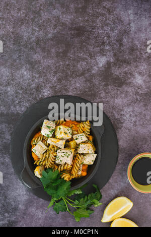 Creamy pumpkin chicken with fusilli pasta. Top view, blank space, dark background Stock Photo