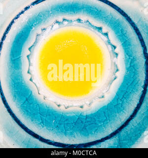 Closeup shot of glazed blue ceramics texture with yellow dot in the middle Stock Photo