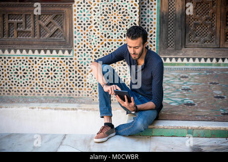 Casual Arab man working on tablet sitting on the floor Stock Photo