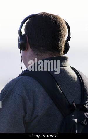 Man wearing wired headphones looking away from camera. Stock Photo