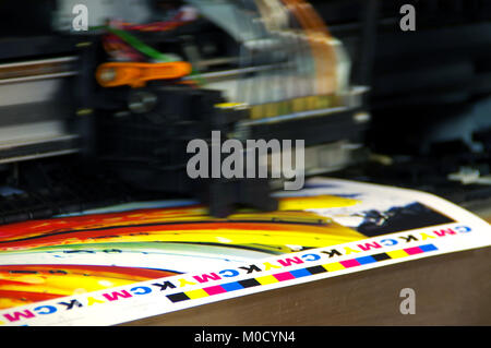 Inkjet plotter printing head moving over CMYK mark on white paper ...