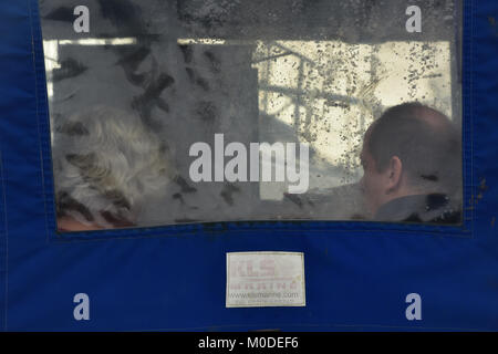 a couple sitting in a boat under the rain cover or canopy talking to each other. plastic window on a pleasure boat with middle aged couple inside cab. Stock Photo