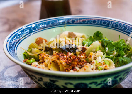 A bowl of biang biang noodles in the Muslim Quarter of Xi’an, China. Sour plum juice drink behind. Stock Photo