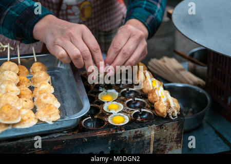 Frying quail eggs on a skewer as street food in the Muslim Quarter of Xi’an, China. One of a series of three. Stock Photo